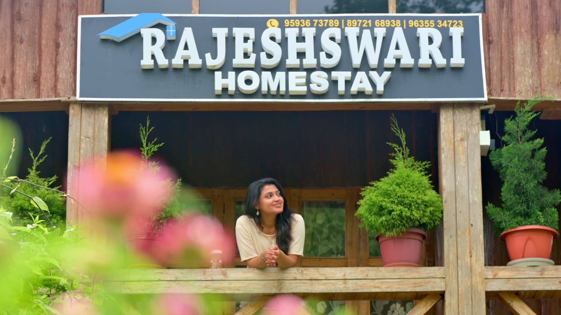A drone-shot image of Rajeshswari Homestay's bulding where a woman can be seen outside the balcony